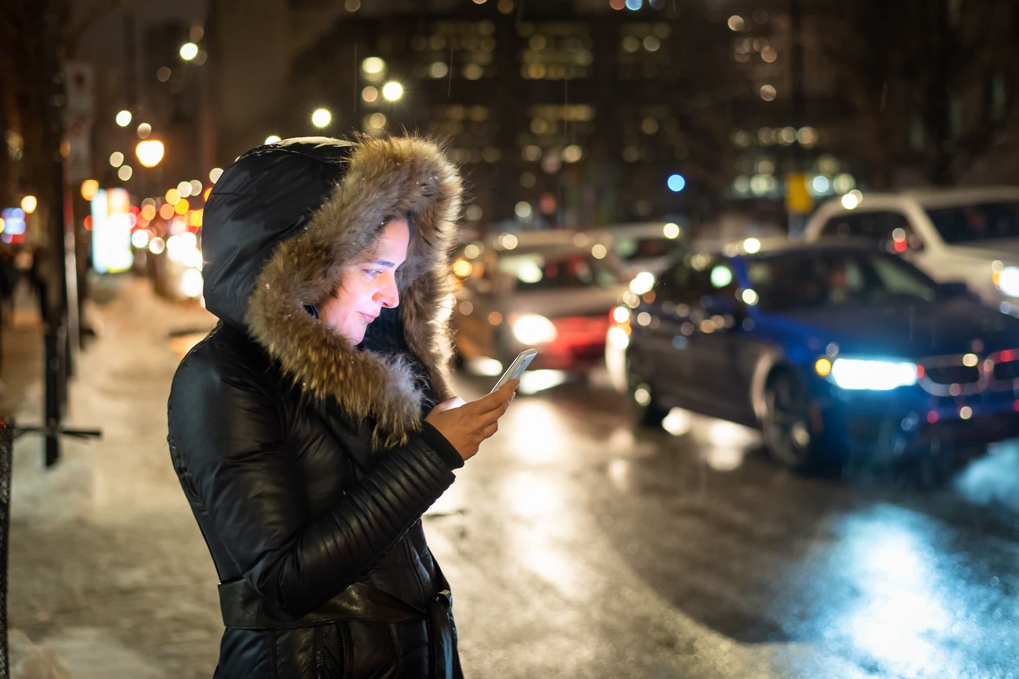 Passenger on a city street using her smartphone, possibly hailing an Uber, amidst the ongoing legal controversies surrounding the rideshare industry.