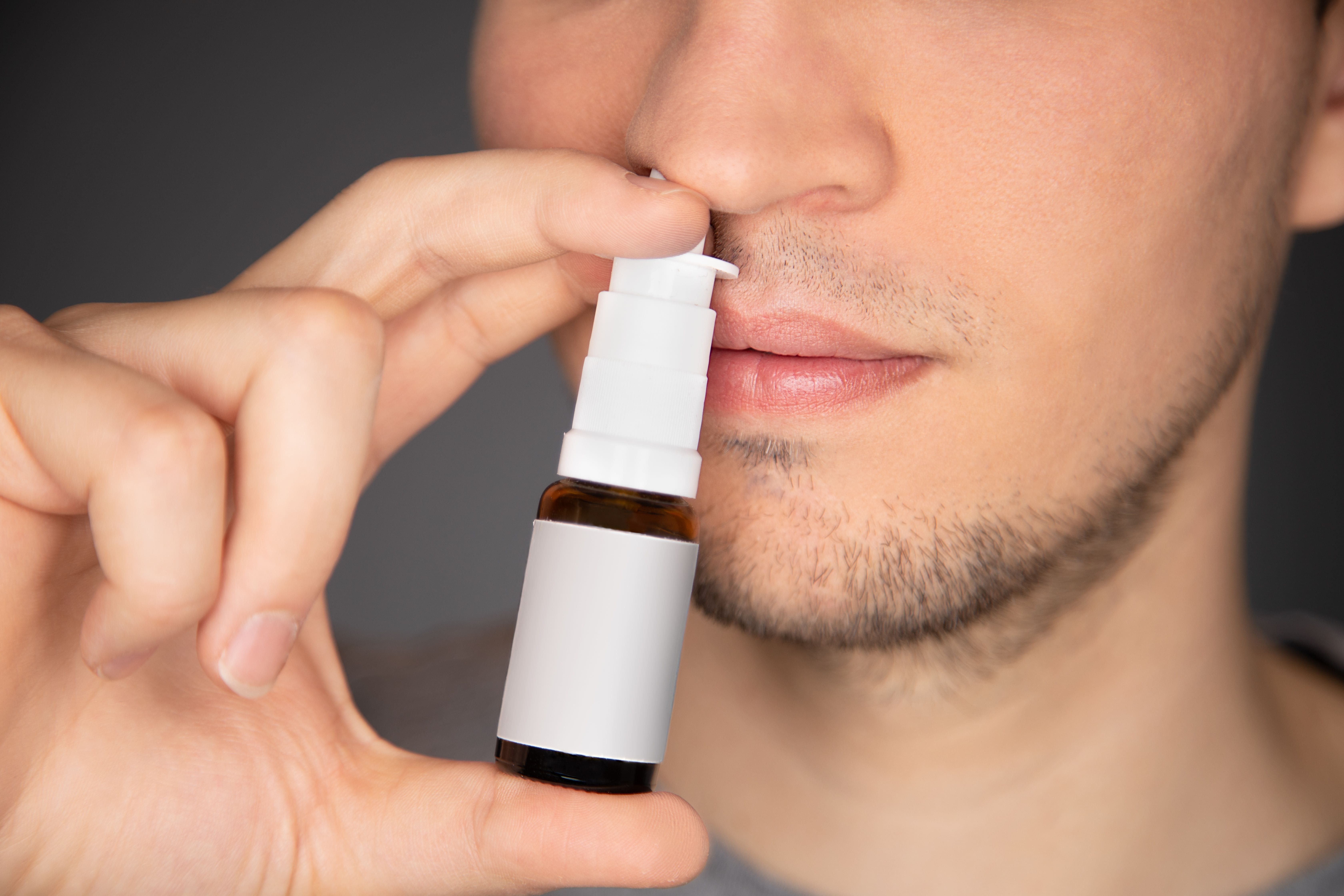 Man using nasal spray by applying the bottle to his nose, in context of Nasal Decongestant Lawsuit article.