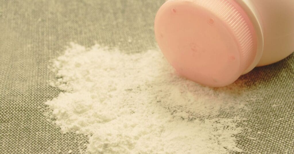 Woman applying baby powder creating a dust cloud that reveals hidden asbestos fibers, representing the talcum powder lawsuit for ovarian cancer and mesothelioma.