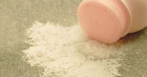 Woman applying baby powder creating a dust cloud that reveals hidden asbestos fibers, representing the talcum powder lawsuit for ovarian cancer and mesothelioma.